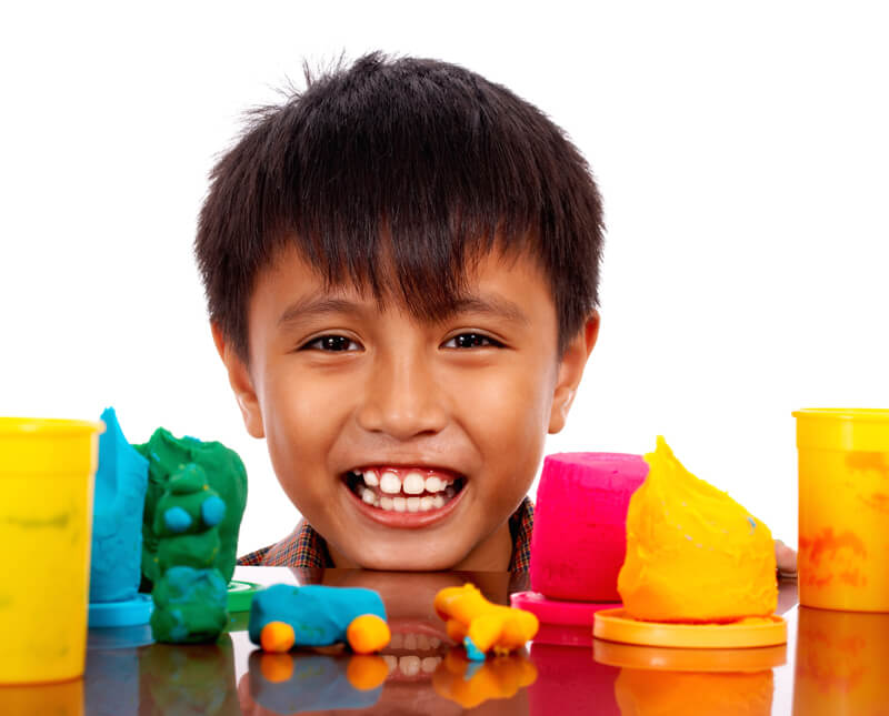 happy boy playing with colored dough