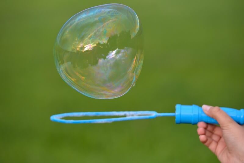 Close up of a soap bubble growing from the blower ring